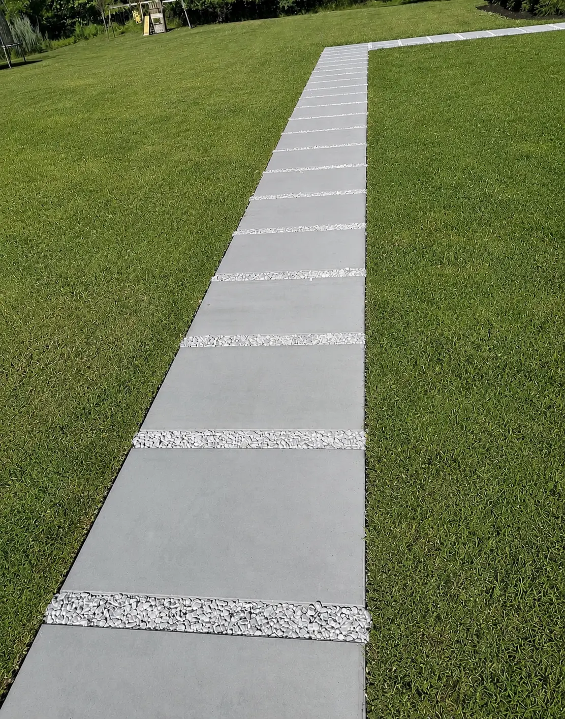 Custom concrete paver walkway with white stone inlays through a green lawn